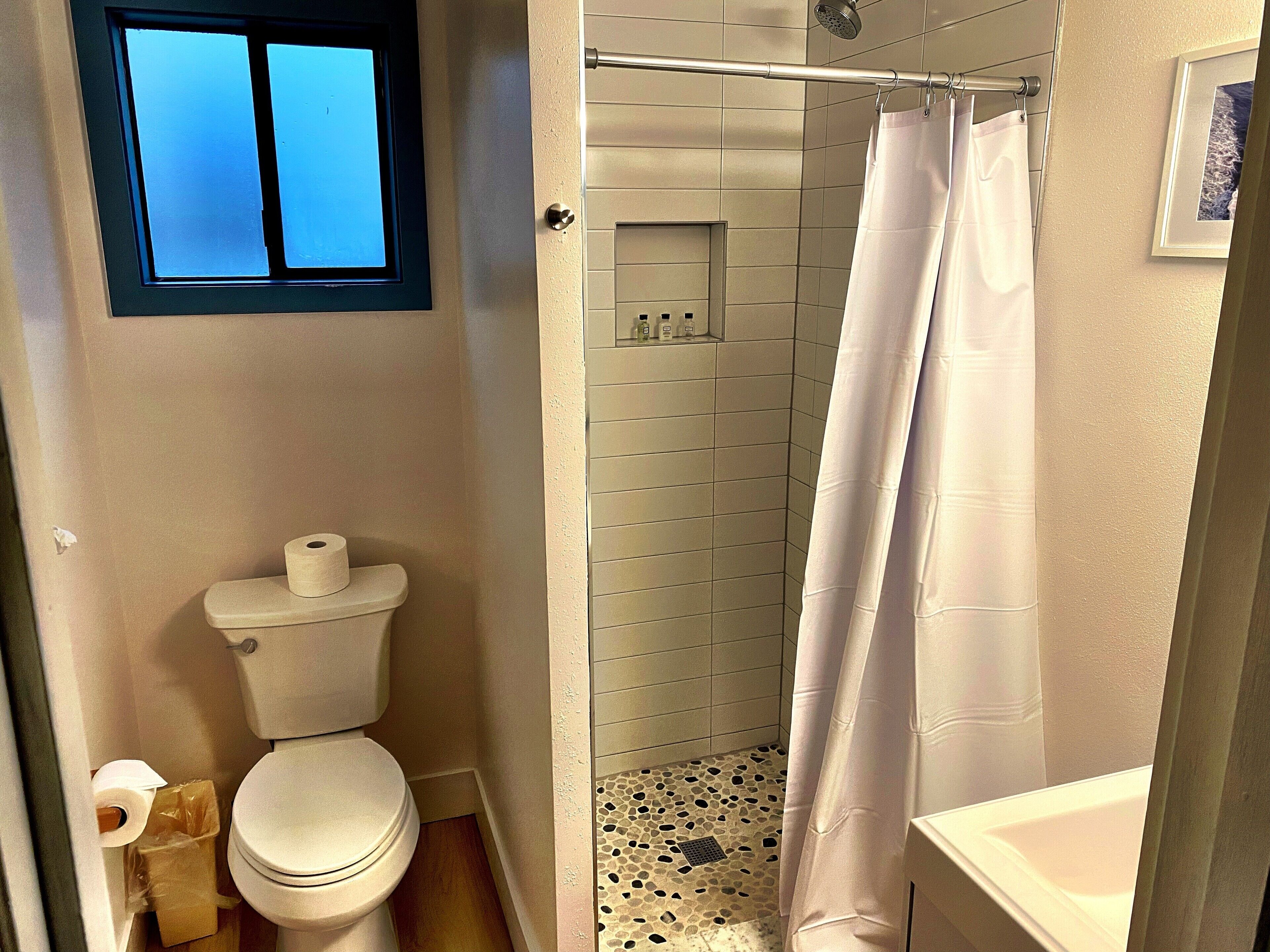 Un bagno con il water, doccia e una piccola finestra.