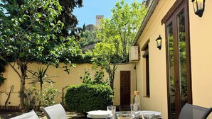 An outdoor dining area with a table set for four, surrounded by greenery and a view of a castle in the distance. - House in front of the Alhambra with a private garden and views (Granada)