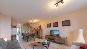 Un salon moderne comprenant un canapé, une table basse, un téléviseur et un escalier menant à une autre pièce.