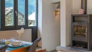 A dining area with a table set for two, a stone wall, and a fireplace. - Rustico Ca' di Garoi by Interhome (Malvaglia)