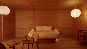 Un dormitorio moderno con una cama grande, suelo de madera y un comedor con mesa y sillas.