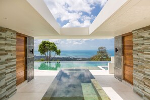 A modern infinity pool with a clear view of the ocean and a tree in the background. - Villa Spice at Lime Samui (Koh Samui)
