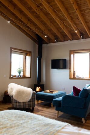 Relax in this inviting room with a high ceiling, two windows, and a comfortable sofa and armchair.