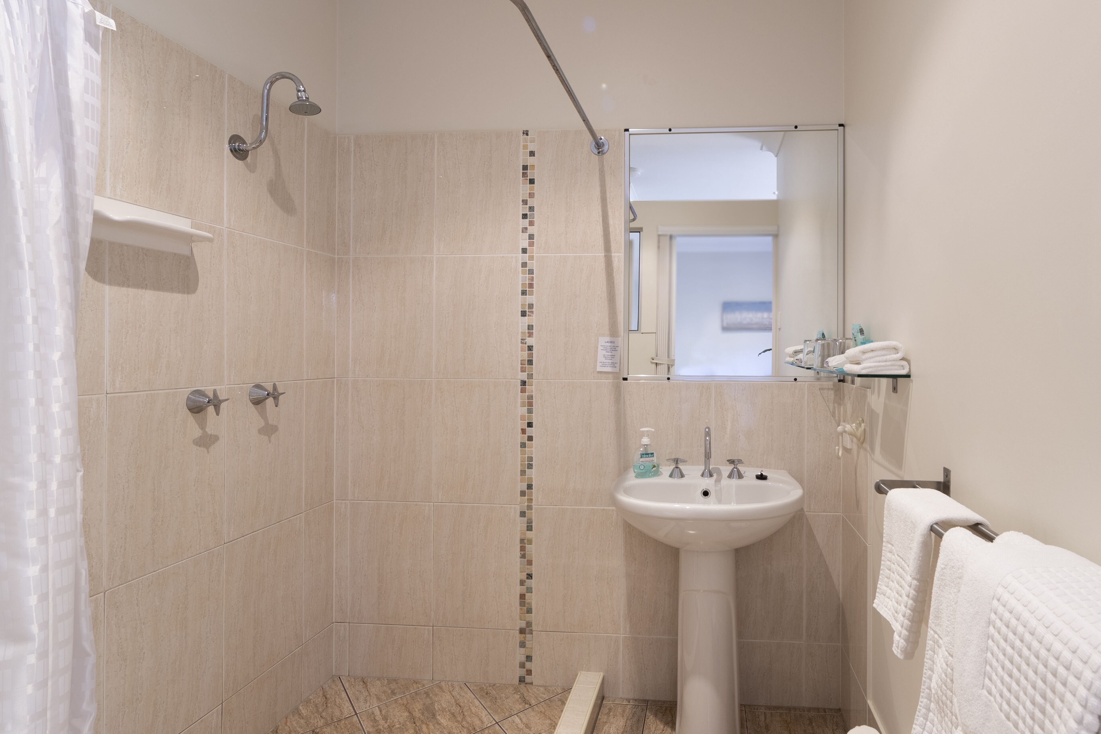 A modern bathroom with a shower, sink, and towel rack.
