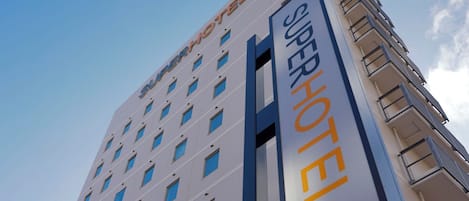 A hotel building with multiple floors, a prominent sign reading "SUPERHOTEL", and balconies on the upper levels.
