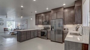 Une cuisine moderne avec des meubles de couleur sombre, des appareils en acier inoxydable et un îlot central.
