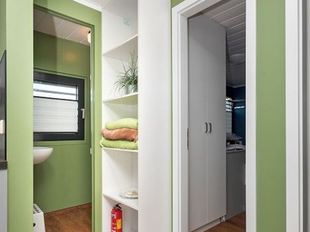 A compact kitchen with a window, a white sink, and a white cabinet with shelves.
