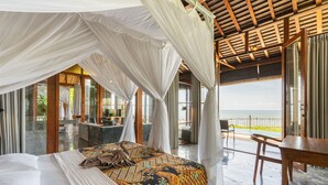 Une chambre avec un grand lit, une table en bois et une vue sur la mer.
