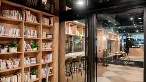 Een boekwinkel met houten schappen vol boeken en potplanten.