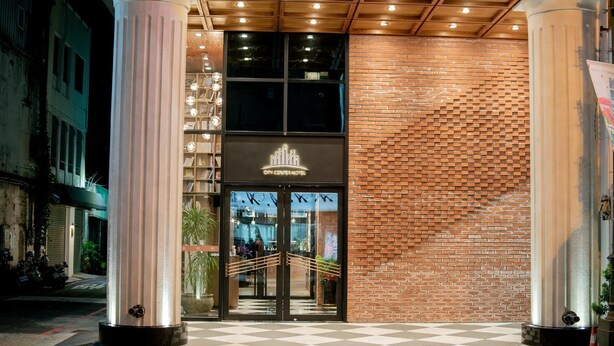 De ingang van Hotel City Center, met een bakstenen gevel, grote glazen deuren en een schakerend vloerpatroon.