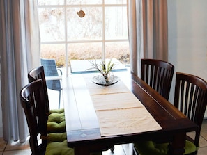 Una mesa de comedor con un centro de mesa con planta, rodeada de sillas.