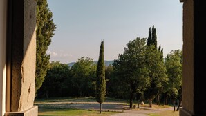 Un portail en arc donnant sur une cour intérieure agrémentée d’arbres et offrant une vue sur un ciel dégagé.