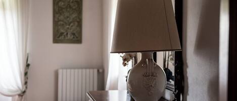 Une pièce avec une lampe sur une commode, un radiateur et un tableau accroché au mur.