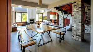 A modern living room with a large wooden table, built-in seating, and a fireplace. - Villa Opuntia (Chania)