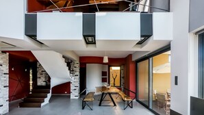 A modern interior with a staircase, a dining area, and a seating area with cushions. - Villa Opuntia (Chania)