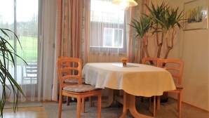 A dining area with a table and four chairs, a hanging light fixture, and a potted plant. - Ferienwohnung Singer (Schnaittach)