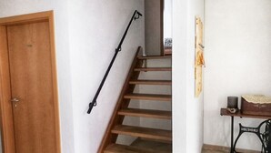 Une porte en bois, un escalier en bois et une petite table avec une chaise.