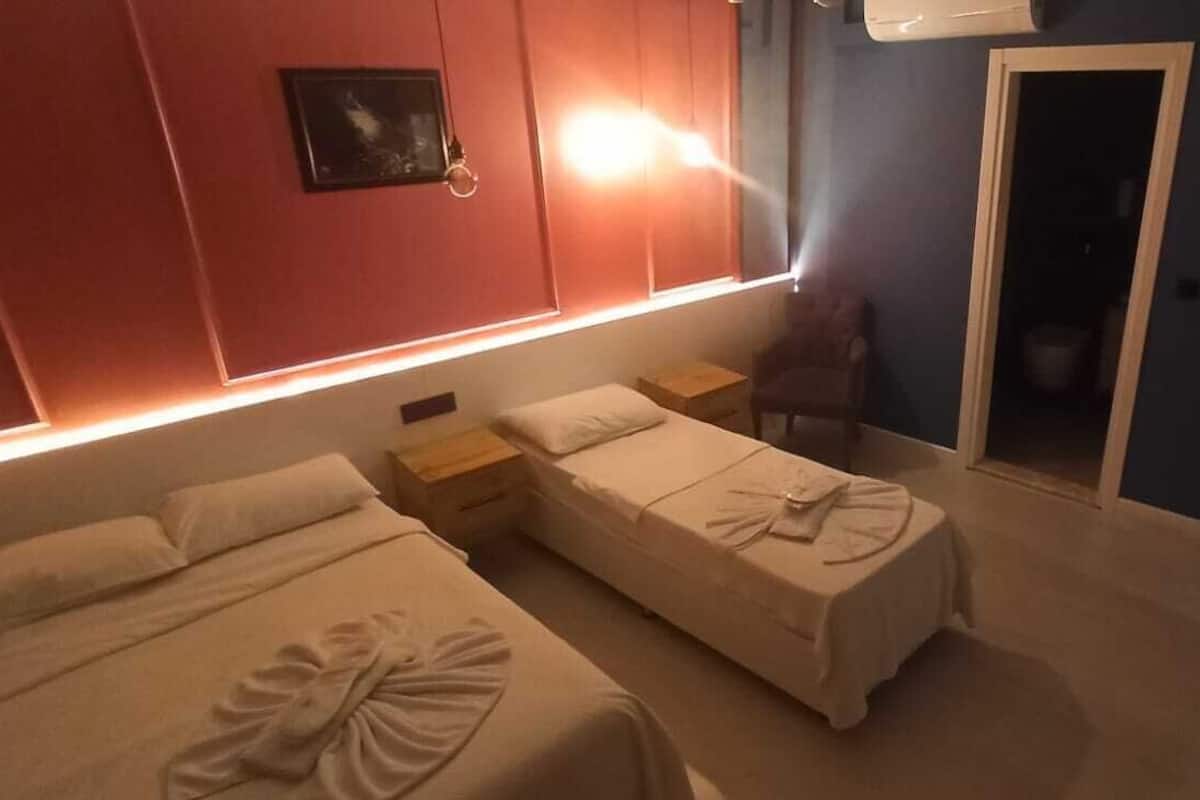 A hotel room with two beds, a nightstand, a chair, and a door leading to a bathroom.