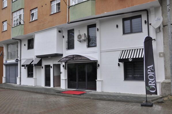 A hotel with a white facade, black awnings, and a red carpet entrance. - Oropa Butik Hotel (Eynesil)
