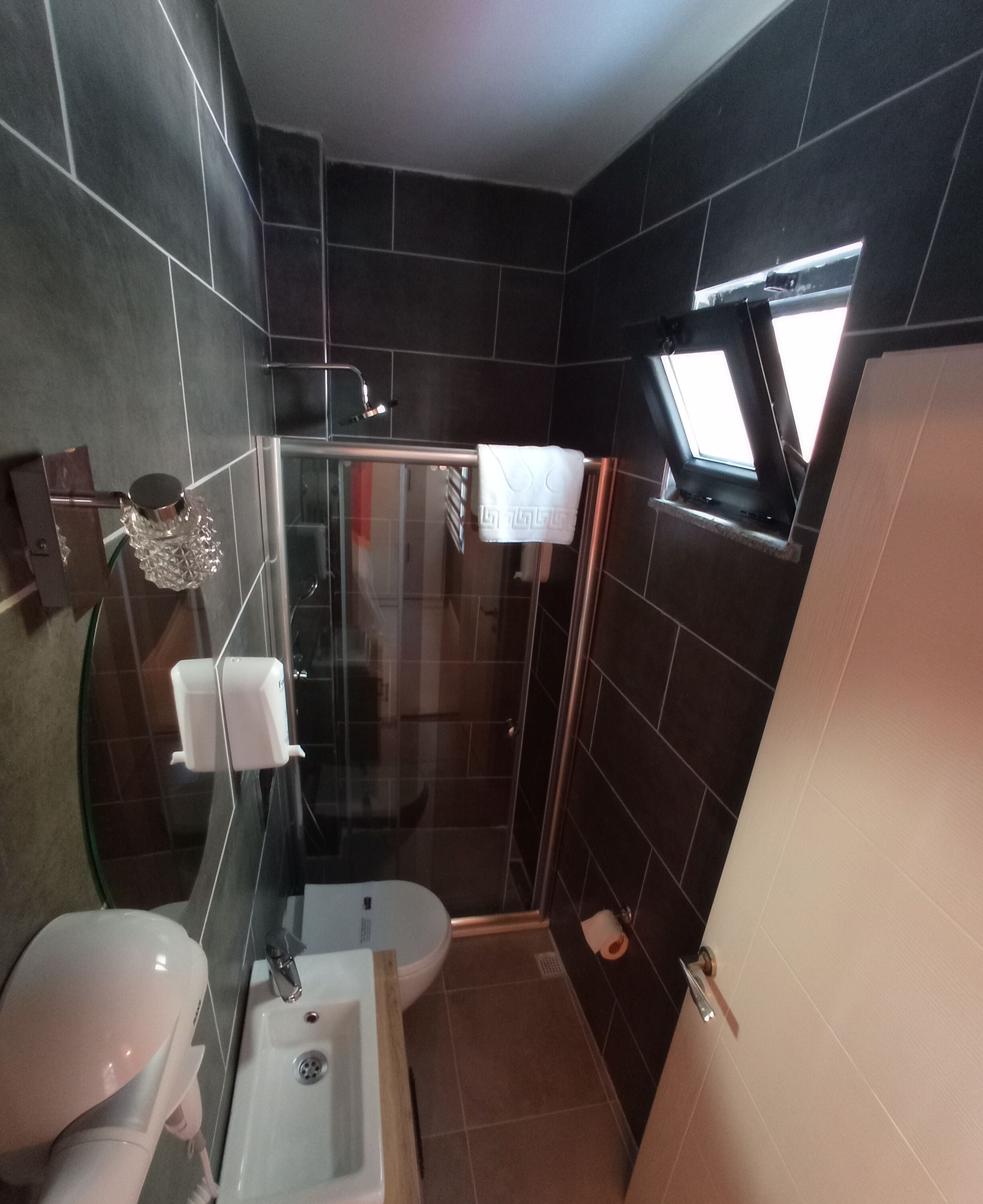 Un baño moderno con ducha de mampara de vidrio, inodoro y lavamanos.