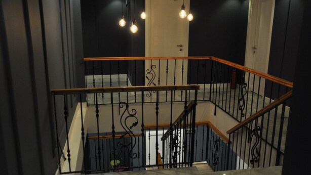 A staircase with black railings and wooden handrails, leading to a landing with a white door marked "705". - Oropa Butik Hotel (Eynesil)