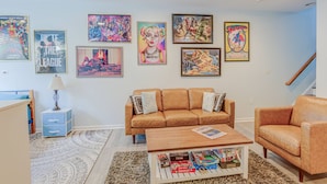 Ein Wohnzimmer mit einem braunen Sofa, einem Couchtisch mit Gesellschaftsspielen und verschiedenen Postern an der Wand.