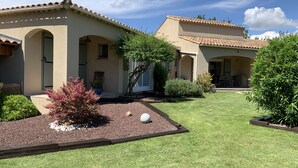 A Mediterranean-style building with arched doorways, a tiled roof, and a well-maintained garden with gravel paths and greenery. - Maison 190m2 Chambres Climatisées, Piscine Privée, Proche Village (Velleron)