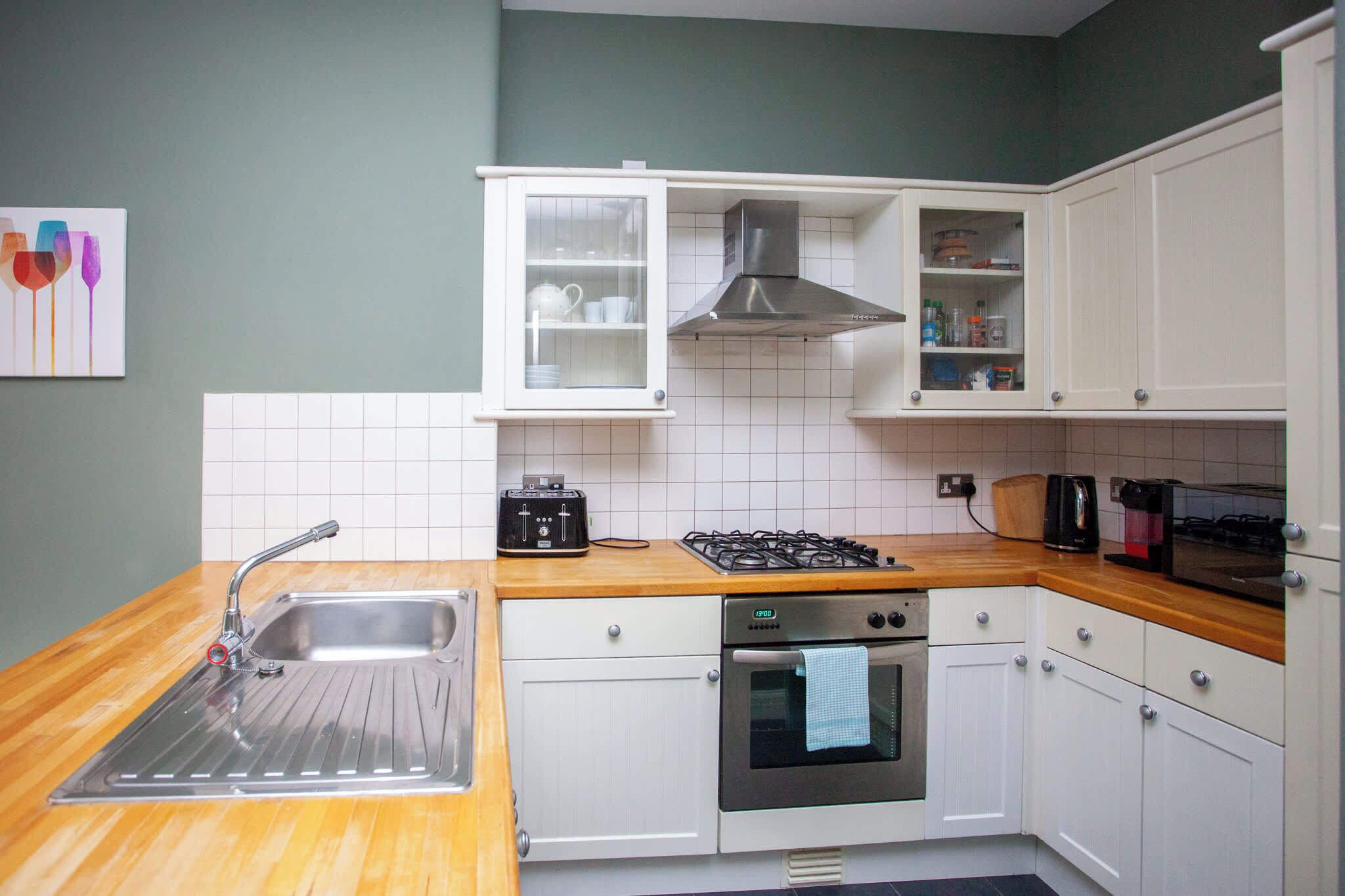 A kitchen with white cabinets, a stainless steel sink, a gas stove, and a built-in oven.