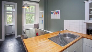 A kitchen with a wooden countertop, stainless steel sink, and white cabinets.