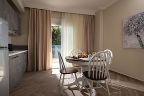 A modern kitchen with a dining area, a view of greenery, and a painting on the wall.