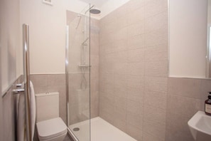 Un baño moderno con ducha envuelta en vidrio, inodoro y lavabo.