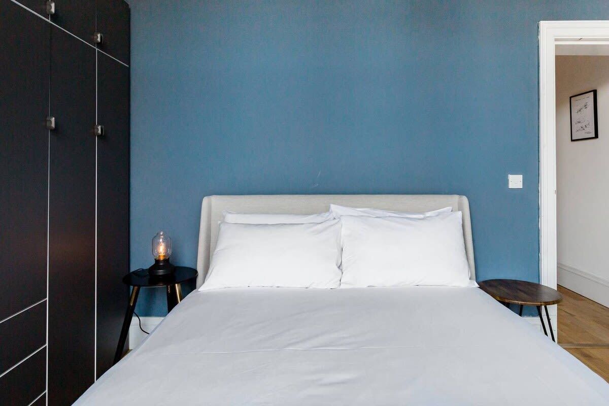 Ein Schlafzimmer mit einem Bett, einem Nachttisch mit Lampe, einem kleinen Tisch und einem Kleiderschrank.