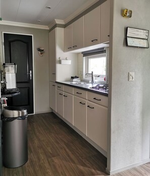 Enjoy cooking in this well-equipped kitchen with a sink, coffee maker, and trash bin, offering a view from the window.