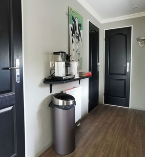 Stylish hallway with a black door on each side and a central door, featuring a coffee machine and a framed picture.