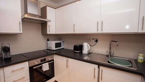 Una cucina moderna con mobili bianchi, un piano di lavoro nero, un forno a microonde, un bollitore, un lavello e un forno Bosch.