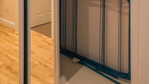 Una stanza con pavimento in legno, una porta scorrevole, un armadio con mensole e appendiabiti, e un oggetto blu sul pavimento.