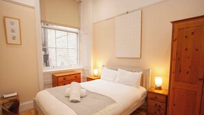 Una camera da letto ordinata con un letto grande, comodini con lampade, un armadio e una finestra con persiane.