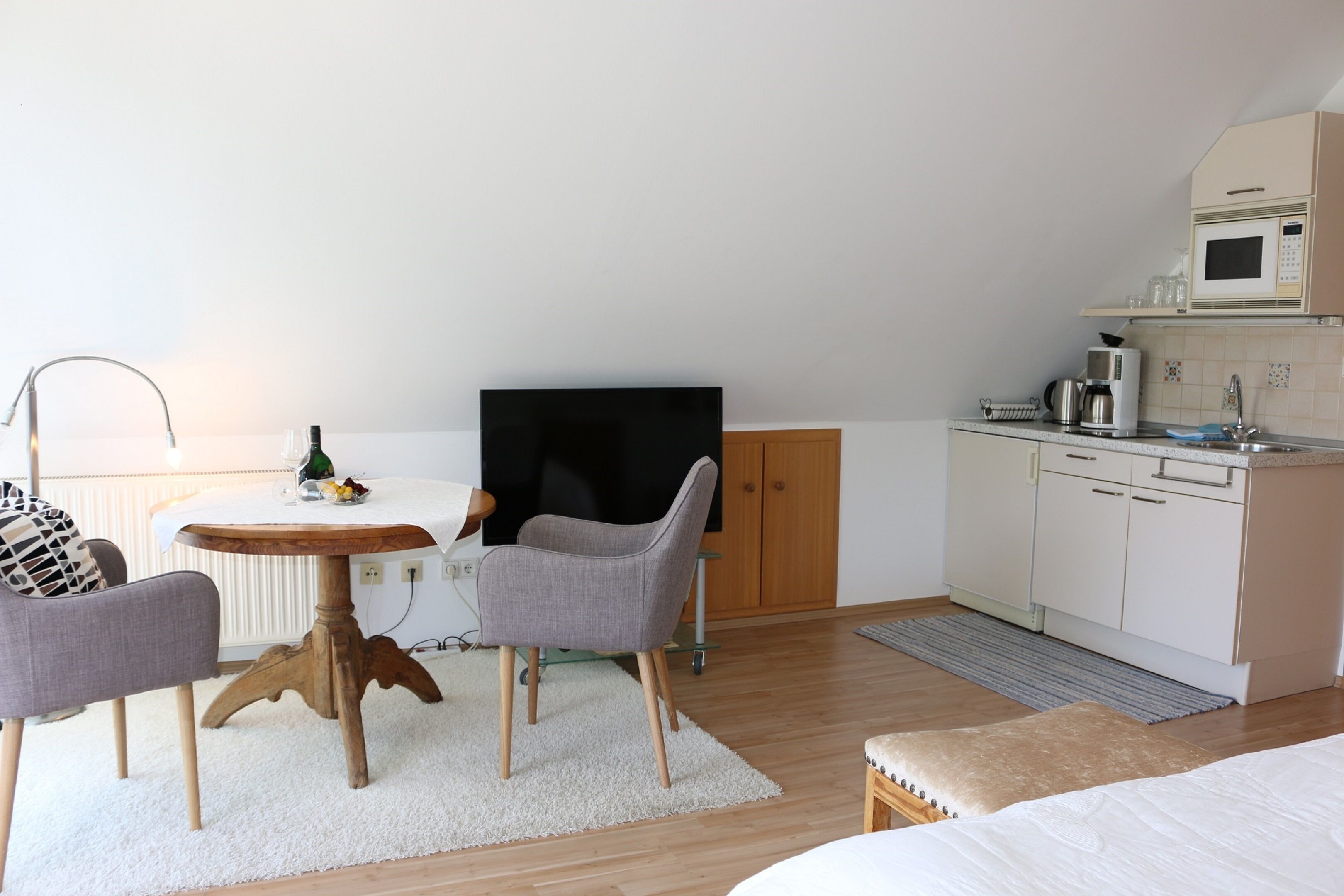 Een gezellige, compacte leefruimte met een eethoek, een kitchenette en een televisie.