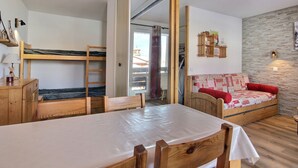 Ett mysigt rum med en våningssäng, ett träbord, en soffa och en vägg av sten.