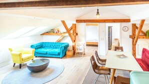 A cozy loft-style living space with a blue sofa, yellow armchair, and a dining table. - Peter-Anderl-Hof (Pfreimd)