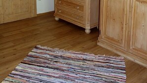 A room with wooden cabinets, a dresser, a mirror, and a striped rug. - Woidhaisl (Lam)