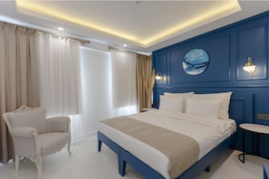 A modern bedroom with a large bed, a chair, and a small table. - Kiana Kaleici (Antalya)