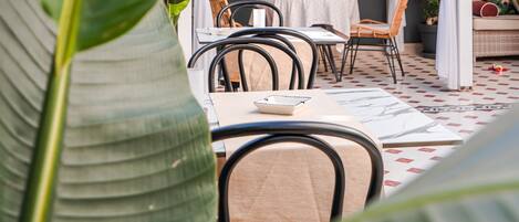 Un patio exterior con una pérgola blanca, una mesa con sillas y una cesta colgante.