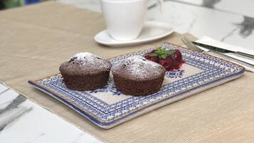 Una mesa con un plato de muffins y una taza de té, un tenedor y un cuchillo sobre un mantel.