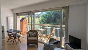 Une chambre avec un balcon, un lit, un bureau et une télévision.