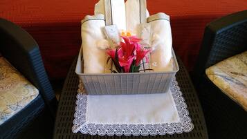 Un plateau avec des serviettes pliées, un petit vase avec des fleurs et une boîte de mouchoirs sur une table recouverte d’une nappe en dentelle.