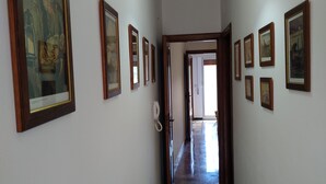 Un pasillo con cuadros enmarcados en las paredes, una lámpara colgante y un teléfono.