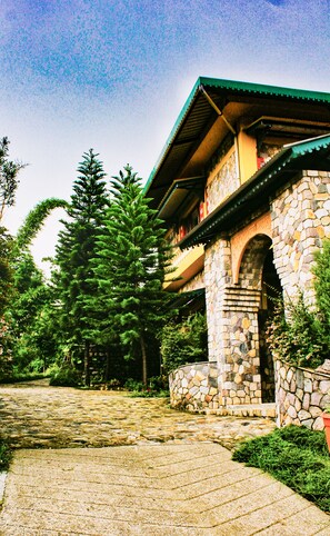 Ein Steinhaus mit grüner Dachdeckung, einer Steintreppe und einem Kopfsteinpflasterweg.