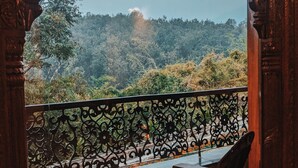A balcony with ornate railings, a table, and two chairs, overlooking a forested hillside. - Tree of Life Resort, Dehradun Foothills (Dehradun)