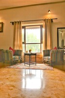 A room with two striped armchairs, a small table with a vase, and a window with curtains.